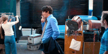 a man is smoking a cigarette while a woman hangs clothes in the background