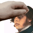 a hand is touching a man 's forehead with a hat on .