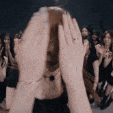 a woman covering her face with her hands in front of a crowd of women