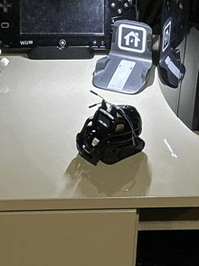 a wii controller sits on a table next to a small black robot