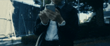 a man in a suit and tie is looking at his cell phone