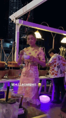 a woman in a pink dress is standing in front of a table with the name bellacampen on the bottom