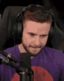 a man wearing headphones and sunglasses is sitting in front of a microphone and making a funny face .