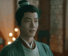 a man with his hair in a bun is smiling