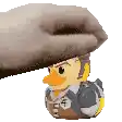a person is holding a rubber duck with a cowboy hat on it .