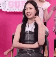 a woman is sitting in a chair with her arms crossed and smiling at the camera .