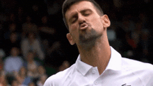 a man with a beard is blowing a kiss while wearing a white shirt .