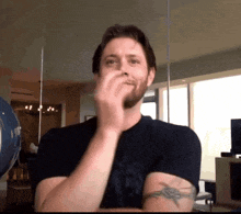 a man in a black shirt with a tattoo on his arm is making a funny face
