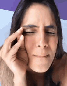 a close up of a woman 's face with her hand on her face