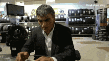 a man in a suit sits at a table in front of tires