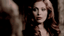 a woman with red hair and blue eyes is looking at the camera