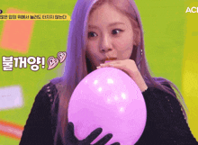 a woman blowing up a pink balloon with chinese writing on it