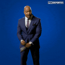 a man in a suit holds up a thumbs up sign in front of a blue background that says fox deportes