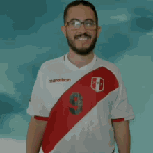 a man wearing glasses and a marathon shirt smiles for the camera