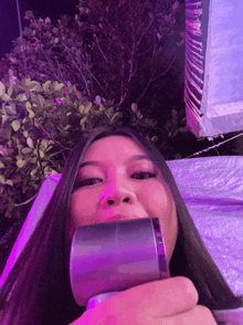 a woman with long hair is holding a purple object in front of her face