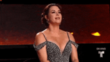 a woman in a dress is sitting in front of a screen that says en vivo on it
