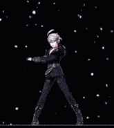a man in a black suit is standing in front of a black background with petals falling around him .