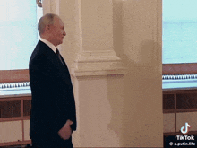 a man in a suit is standing in a room with his hands in his pockets