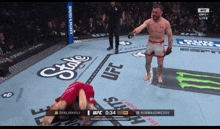 a man in a red shirt is kneeling on the ground in a ufc ring