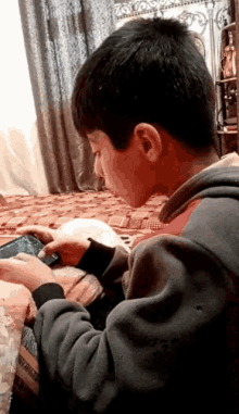 a young boy is playing a game on a cell phone