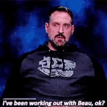 a man with a beard is wearing a shirt that says i 've been working out with beau , ok ?