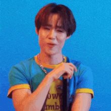 a young man is smiling while holding a microphone in his hand .