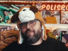 a man with a beard wears a stuffed dog hat and glasses