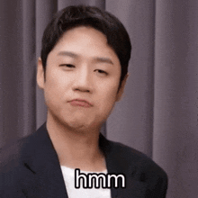 a man in a suit is making a funny face and saying hmm