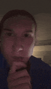 a man in a blue shirt is making a funny face with his fingers