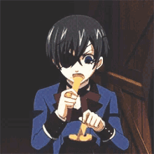 a boy in a blue suit is holding a knife and a piece of food in his hands .