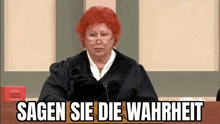 a judge with red hair is sitting in front of a microphone in a courtroom and saying sagen sie die wahrheit .