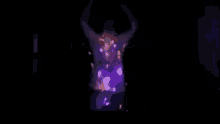 a man in a cowboy hat is dancing in a dark room with christmas lights around his neck .