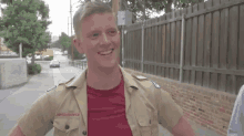 a young man in a boy scout uniform is smiling while standing on the sidewalk .