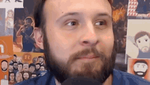 a man with a beard is looking at the camera in front of a wall with pictures of people and the letter h on it