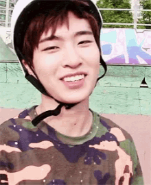 a young man wearing a helmet and a camo shirt smiles for the camera