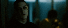 a man with a broken eye is standing in a dark room .