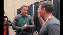 a man wearing a lanyard that says ' a ' on it talks to another man
