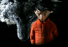 a boy in a red jacket stands in front of a large wolf