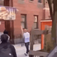 a man is walking down a street in front of a brick building
