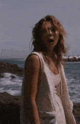 a woman standing on a rock near the ocean