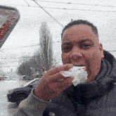 a man wearing a black vest with a tommy hilfiger logo on it is eating something