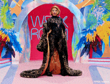 a woman in a leopard print outfit is standing in front of a wall that says week