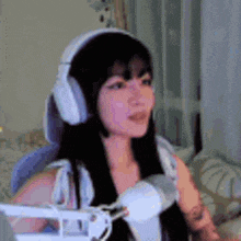 a woman wearing headphones and a microphone is sitting in front of a computer .