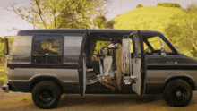 a woman sits in the back of a ram van with its doors open