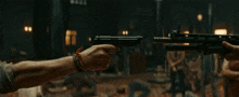 a man is holding a gun in front of a group of people including a woman in a red dress