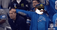 a man wearing a detroit lions shirt stands in the stands with his arm outstretched