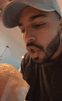 a man with a beard wearing a hat is eating a burger