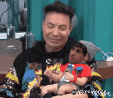 a man is holding a baby in his arms and the baby is wearing a red shirt