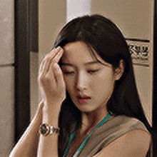 a woman wearing a watch and a lanyard is holding her head .