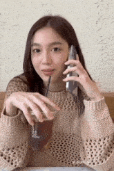 a woman talking on a cell phone while drinking from a cup that says 04 rom on it